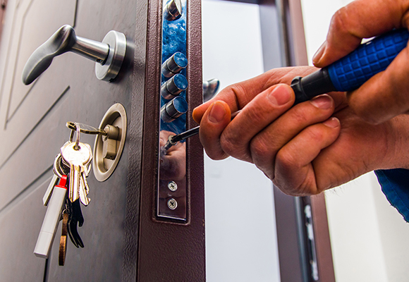 a person using a blue screwdriver to fix a person's door